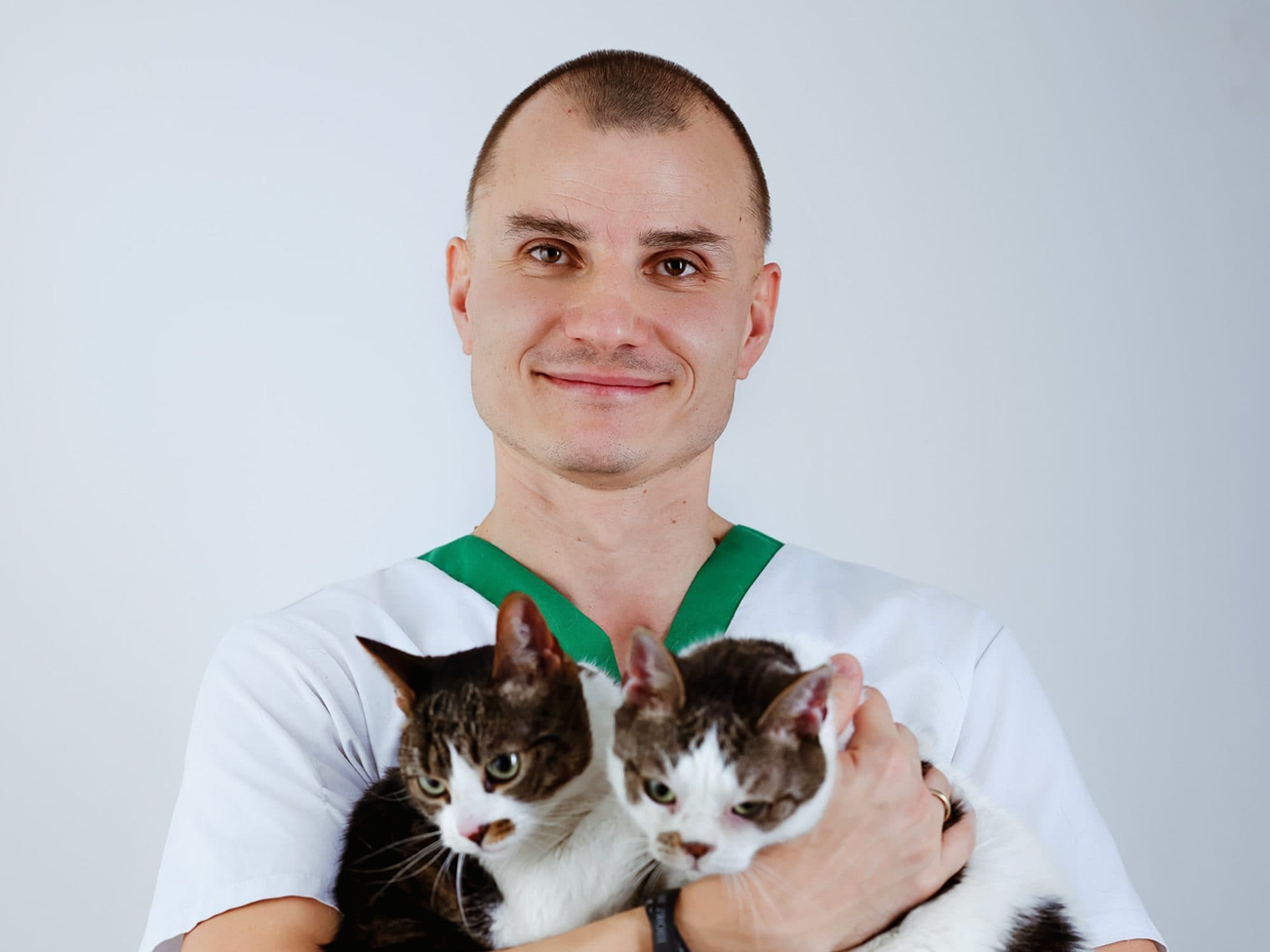 Veterinarian Karol Kunicki holding two cats in his arms